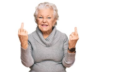 Senior grey-haired woman wearing casual winter sweater showing middle finger doing fuck you bad expression, provocation and rude attitude. screaming excited 