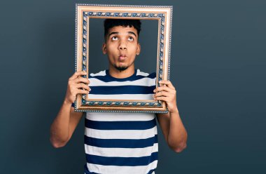 Genç Afro-Amerikan adam elinde boş bir çerçeve ile balık suratlı ve şaşı gözlü, çılgın ve komik.. 