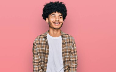 Afro saçlı, siyah saçlı, yüzünde gülümsemeyle yan yana bakan Afro-Amerikalı genç bir adam. Kendinden emin gülen. 