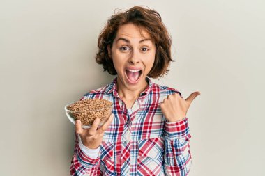 Genç esmer kadın mercimeği fırına verip başparmağını yana uzatıyor ve ağzı açık gülümsüyor. 