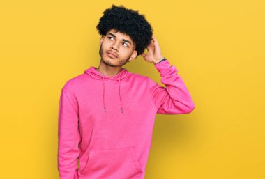 Afro saçlı, günlük pembe kazak giyen Afro-Amerikalı genç bir adam kafası karışıyor ve soru soruyor. Şüpheyle kararsız, kafa kafaya düşünerek. Düşünceli kavram. 