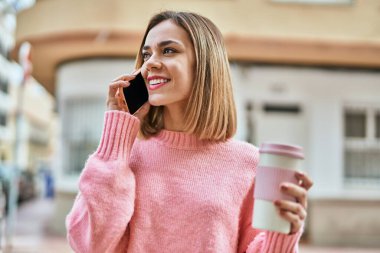 Kafkasyalı genç bir kız akıllı telefondan konuşuyor ve şehirde kahve içiyor..