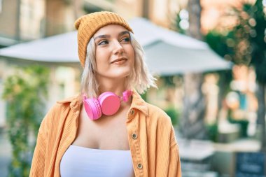 Şehirde kulaklık takan genç sarışın kız..