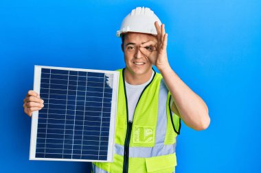 Fotovoltaik güneş paneli tutan yakışıklı genç adam gülümsüyor. 