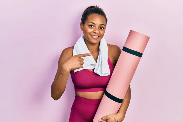 Joven Afroamericana Americana Usando Ropa Deportiva Sosteniendo Esterilla Yoga Sonriendo —  Fotos de Stock