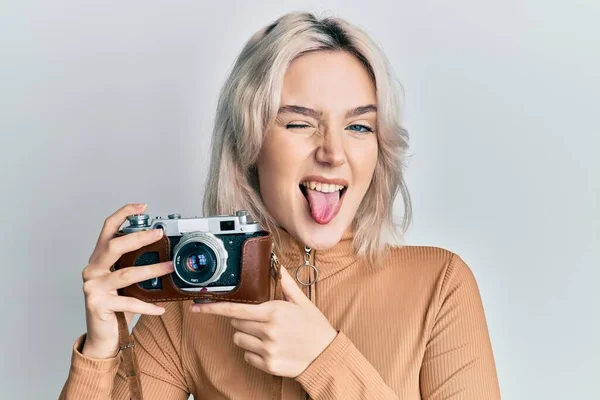 Menina Loira Jovem Segurando Câmera Vintage Piscando Olhando Para Câmera — Fotografia de Stock
