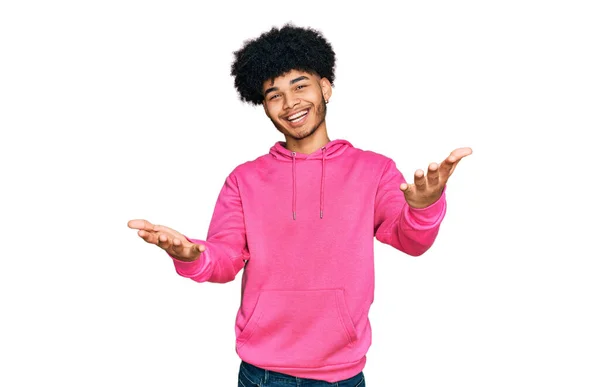 Молодой Африканский Американец Афроволосами Розовой Толстовке Улыбающийся Весело Предлагая Руки — стоковое фото