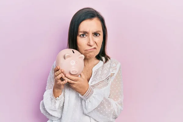 Middelbare Leeftijd Spaanse Vrouw Houden Spaarvarken Bank Shock Gezicht Zoek — Stockfoto