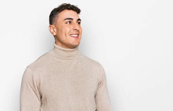 스페인 청년은 평상복 터틀넥 스웨터를 얼굴에 미소를 머금고 고개를 돌리며 — 스톡 사진