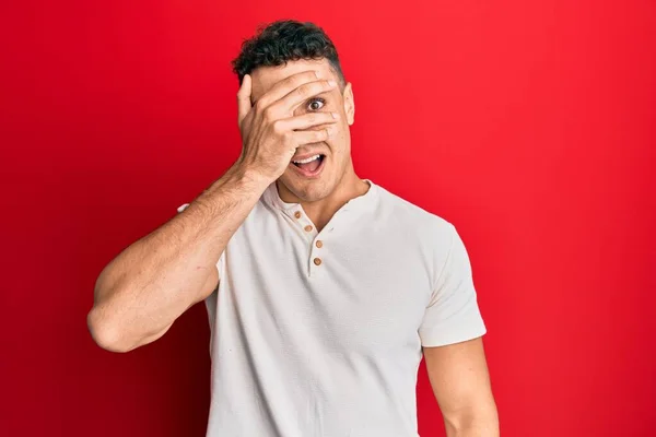 Joven Hispano Vistiendo Una Camiseta Blanca Casual Asomándose Con Mano — Foto de Stock