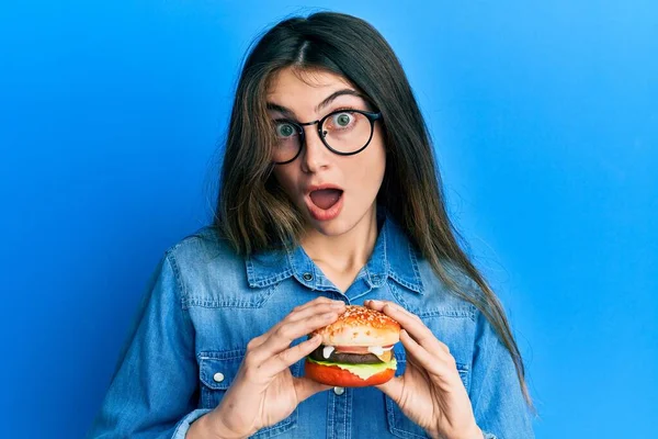 Joven Mujer Caucásica Comiendo Una Sabrosa Hamburguesa Clásica Asustada Sorprendida —  Fotos de Stock