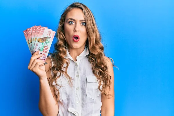 Joven Chica Rubia Sosteniendo 100 Billetes Nueva Zelanda Dólares Asustado —  Fotos de Stock
