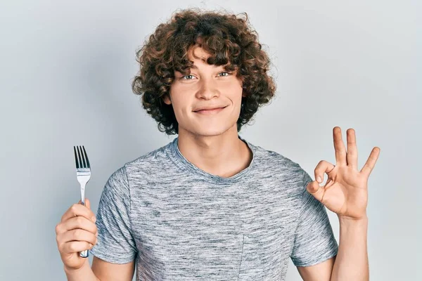 Bonito Jovem Segurando Garfo Prata Fazendo Sinal Com Dedos Sorrindo — Fotografia de Stock