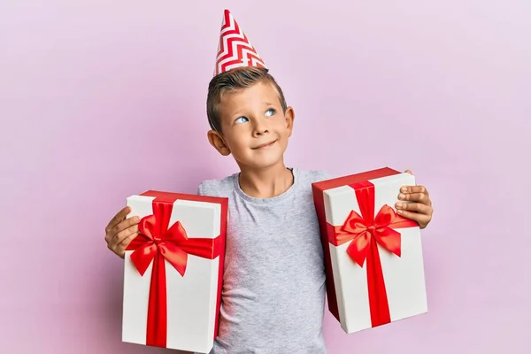 Schattige Blanke Jongen Met Een Verjaardagshoed Met Cadeautjes Aan Zijkant — Stockfoto