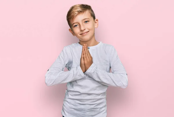 小さな白人の男の子子供が手で祈っているカジュアルな服を着て一緒に笑顔自信を許しを求めて — ストック写真
