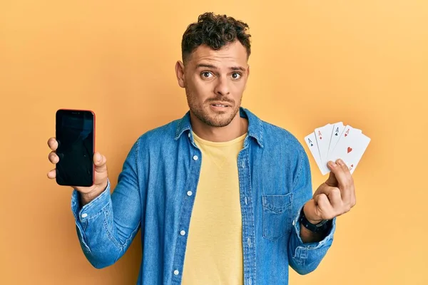 Jovem Hispânico Segurando Cartões Poker Smartphone Mostrando Tela Branco Rosto — Fotografia de Stock