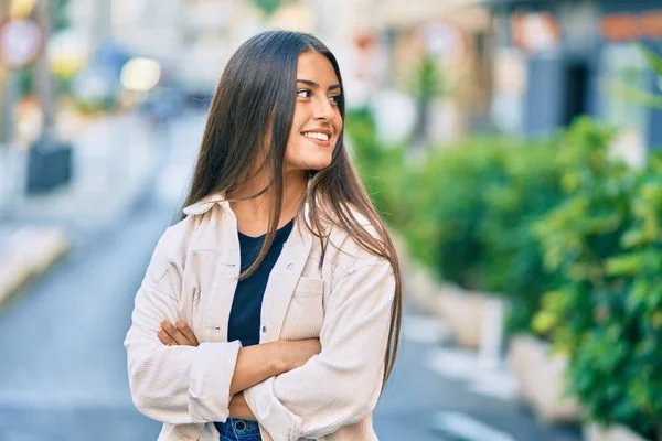Kollarını kavuşturmuş genç İspanyol kız şehirde mutlu bir şekilde gülümsüyor..