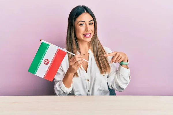 Jovem Hispânica Segurando Bandeira Iran Sentado Mesa Sorrindo Feliz Apontando — Fotografia de Stock