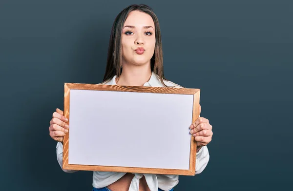 Young Hispanic Woman Holding Empty White Chalkboard Looking Camera Blowing — Stock Photo, Image