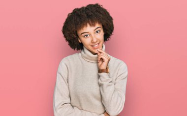 Kışlık yün kazak giyen genç İspanyol kız kameraya kollarını kavuşturup gülümseyen ve çenesini kaldıran kendinden emin bir şekilde bakıyor. Olumlu düşünmek. 