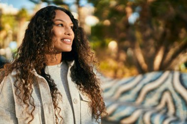 Genç Latin kadın gülümseyerek şehirde mutlu mesut duruyor..