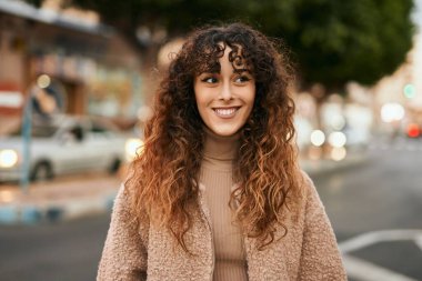 Genç İspanyol kadın gülümseyerek şehirde mutlu mesut dikiliyor.