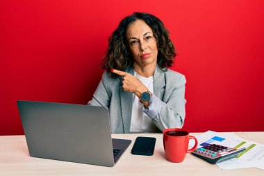 Ofiste çalışan orta yaşlı güzel bir kadın bir fincan kahve içerken elini kaldırmış reklamını yapıyor, ciddi ve sakin bir yüz ifadesi var. 