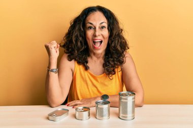 Güzel orta yaşlı kadın konserve yiyeceklerle gururla bağırıyor zaferi kutluyor ve başarıyı kollarını kaldırarak kutluyor. 