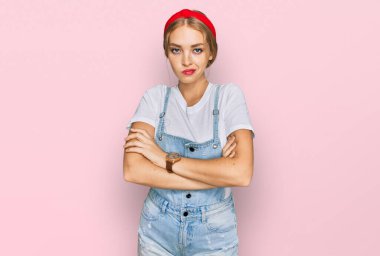 Gündelik kıyafetler giyen, kuşkucu ve gergin genç beyaz bir kız. Yüzünde çapraz kollarla onaylamayan bir ifade var. negatif kişi. 