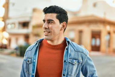 Genç İspanyol adam gülümseyerek şehirde mutlu mesut dikiliyor..