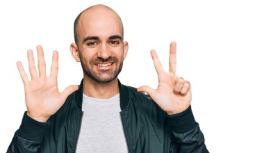 Gündelik kıyafetler giyen genç İspanyol adam sekiz numarayı gösterip işaret ederken kendinden emin ve mutlu bir şekilde gülümsüyor.. 