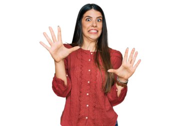 Günlük kıyafetler giyen genç İspanyol kadın korku ifadesinden korkuyor ve dehşete düşüyor. El hareketlerini durdur, şok içinde bağır. panik konsepti. 