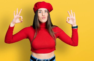 Genç esmer ergen güzel ve seksi bir şekilde öpüşürken kameraya bakarak harika bir jest yapıyor. aşk ifadesi. 