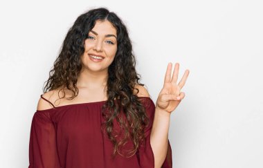 Gündelik kıyafetler giyen genç İspanyol kız üç numarayı gösterip işaret ederken kendinden emin ve mutlu bir şekilde gülümsüyor.. 