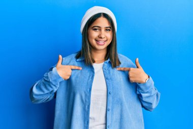 Şirin yün şapkalı, kendine güvenen, gülümseyen, kendini gururlu ve mutlu gösteren genç Latin bir kadın.. 