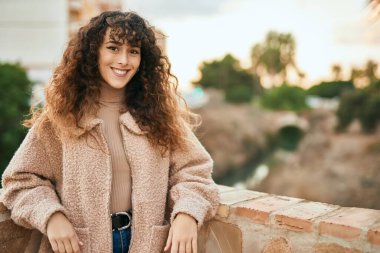 Genç İspanyol kadın gülümseyerek şehirde mutlu mesut dikiliyor.