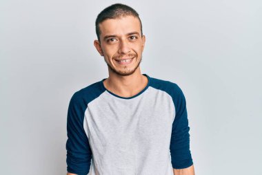Yüzünde mutlu ve havalı bir gülümseme olan gündelik kıyafetler giyen İspanyol genç bir adam. şanslı kişi. 