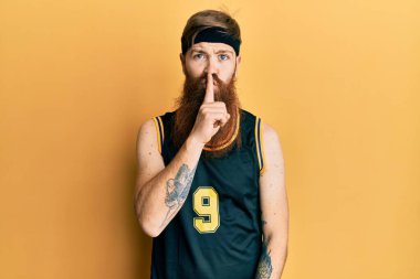 Uzun sakallı, basketbol forması giyen kızıl saçlı adam sessiz olmak istiyor. sessizlik ve gizli konsept. 