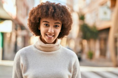 Genç İspanyol kız gülümseyerek şehirde mutlu mesut dikiliyor..