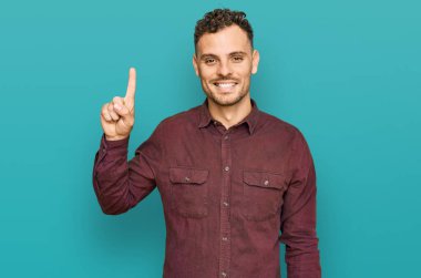 Gündelik kıyafetler giyen genç İspanyol adam başarılı bir fikirle işaret ediyor. Heyecanlı ve mutlu. Bir numara.. 