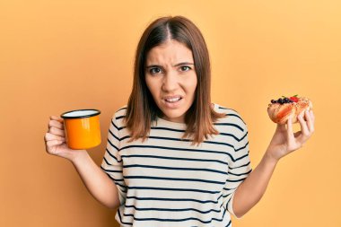 Genç, güzel bir kadın kahve içiyor, hamur işi yiyor, habersiz ve kafası karışık. şüphe kavramı. 