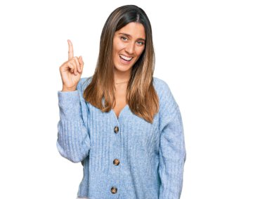 Gündelik giysiler giymiş genç bir kadın başarılı bir fikirle işaret ediyor. Heyecanlı ve mutlu. Bir numara.. 