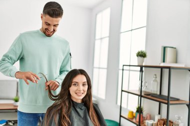 Genç İspanyol stilisti kadın saçını güzellik merkezinde makas kullanarak kesiyor..