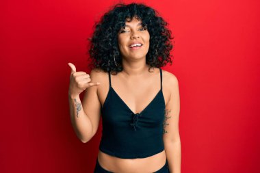 Kolsuz tişörtlü, sıradan giyinen genç İspanyol kadın telefonla el ve parmak hareketleriyle gülümsüyor telefonda konuşur gibi. iletişim kavramları. 