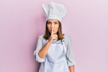 Profesyonel aşçı üniforması giyen ve şapkası olan genç ve güzel bir kadın sessiz olmak istiyor. sessizlik ve gizli konsept. 