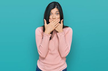 Gündelik kıyafetler giyen genç İspanyol kadın yanlışlıkla elleri ile ağzını kapatırken şok oldu. gizli kavram. 