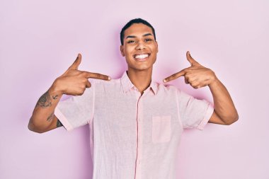 Genç, Afro-Amerikalı, günlük kıyafetler giyen, kendine güvenen, gülümseyen, kendini gururlu ve mutlu gösteren bir adam.. 