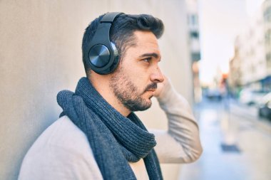 Gevşek yüzlü, şehirde kulaklık takıp müzik dinleyen genç bir İspanyol..