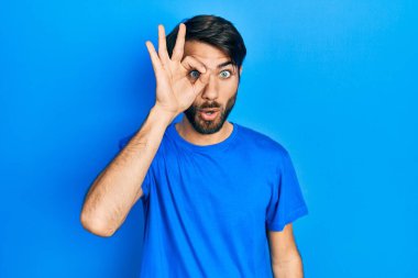 Gündelik kıyafetler giyen genç İspanyol adam şaşırmış yüz ifadesiyle şok olmuş, parmaklarından bakan gözler. İnançsız ifade. 