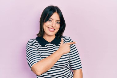 Yüzünde mutlu ve doğal bir ifade olan, elleri ve parmaklarıyla işaret eden, güler yüzlü, gündelik kıyafetler giyen genç İspanyol kadın. 